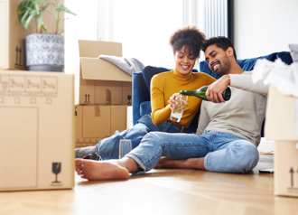 Couple sat down and drinking champagne to celebrate after moving in