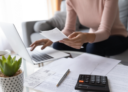 income Woman looking at a laptop and pieces of paper